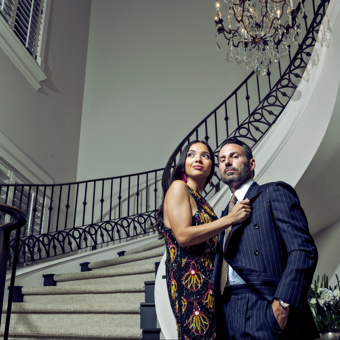 Glamourous couple poses on grand staircase in central Texas home for Great Gatsby photoshoot