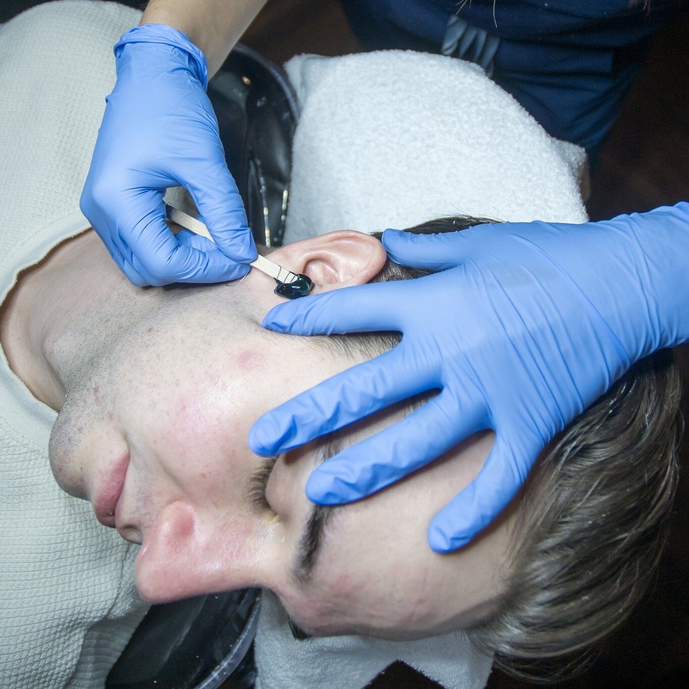 waxing a male client's ear at Flycatcher